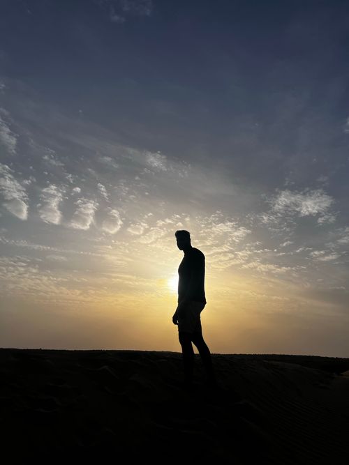 Free Silhouette of a person walking against a dramatic sunset in Rajasthan desert. Stock Photo