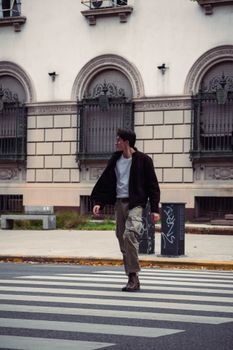 A man walks across a crosswalk in Buenos Aires amid autumn urban scenery.