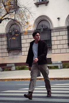 Man crossing a city street in fall, dressed in a casual outfit in Buenos Aires.