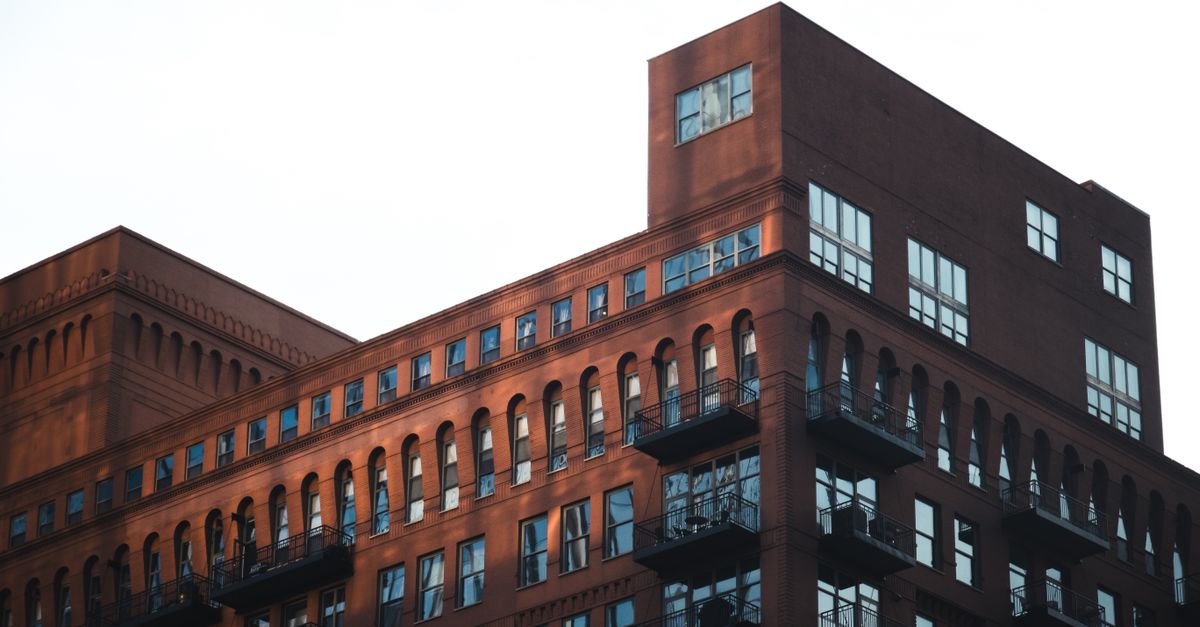 A modern industrial-style brick building with balconies and large windows.