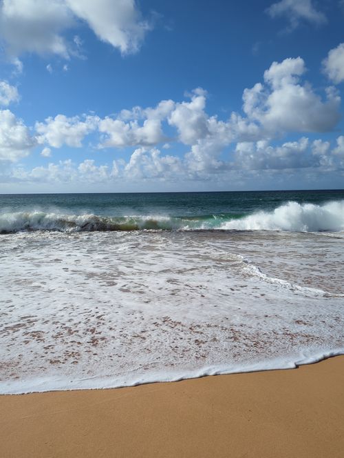 Free Calm ocean waves lapping on a sandy beach under a bright blue sky Stock Photo
