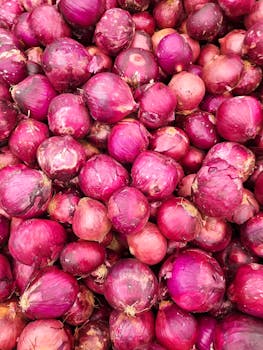 A vibrant photo showcasing a heap of fresh red onions at a market in Brasil.
