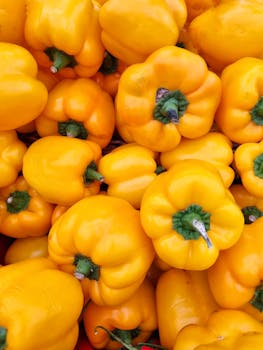 A vibrant display of yellow bell peppers, fresh and ready for sale at a Brazilian outdoor market.
