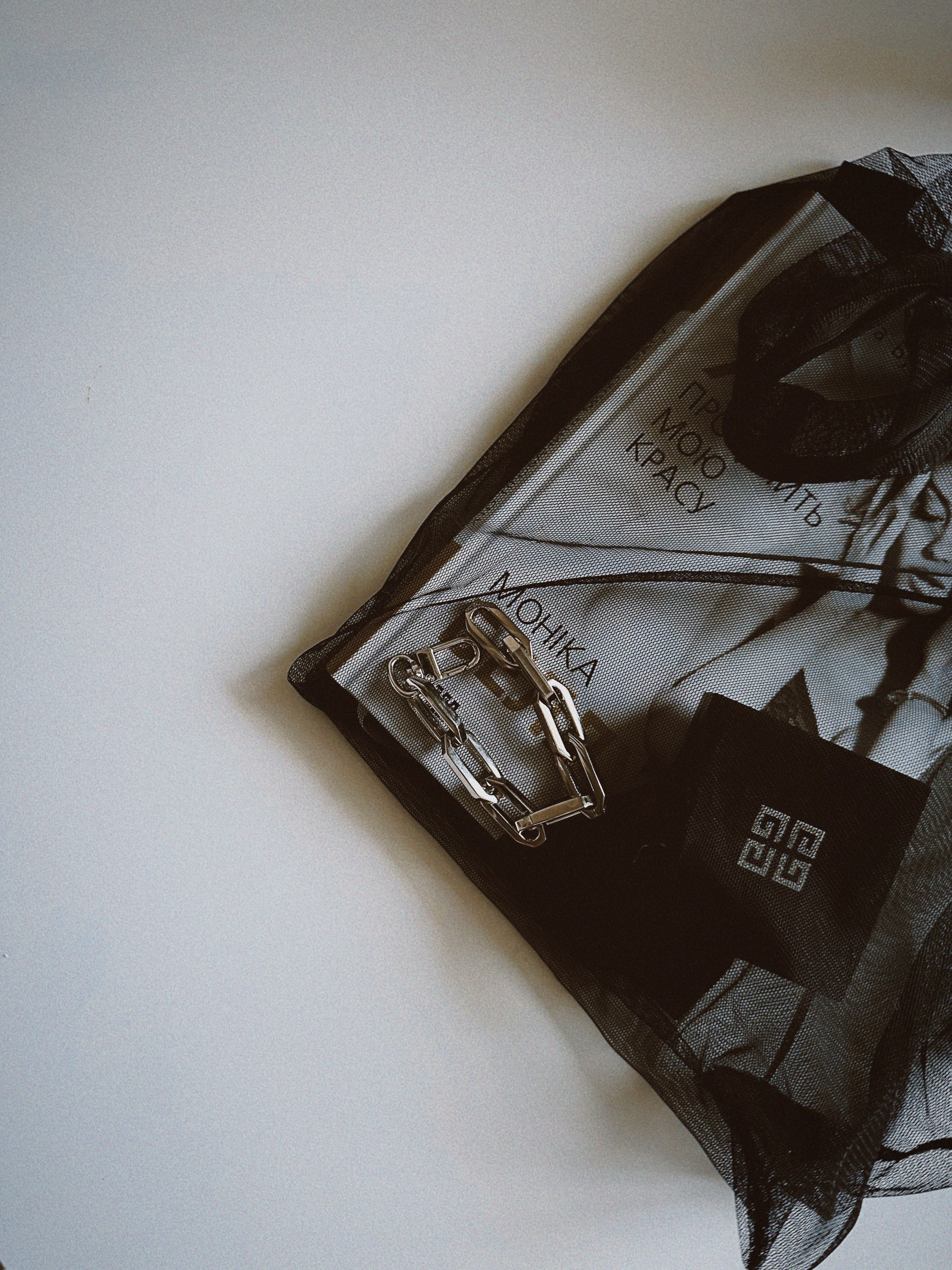 Modern black tote bag with unique Monika design and silver chain accessory.