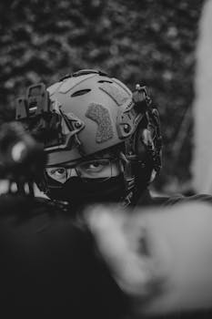 Close-up black and white photo of a soldier wearing tactical helmet and mask.