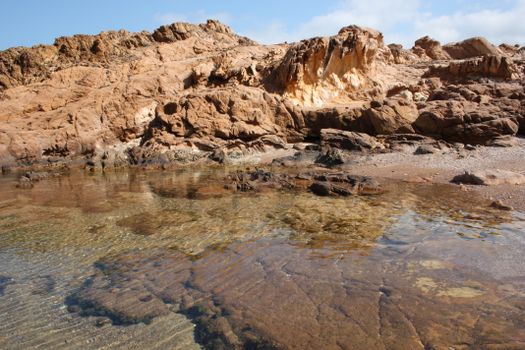 A tranquil rocky shoreline with clear tide pools reflecting the clear skies.. pexels, tranquil, rocky