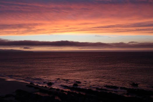 A serene ocean view at sunset with vibrant, colorful skies and gentle waves.