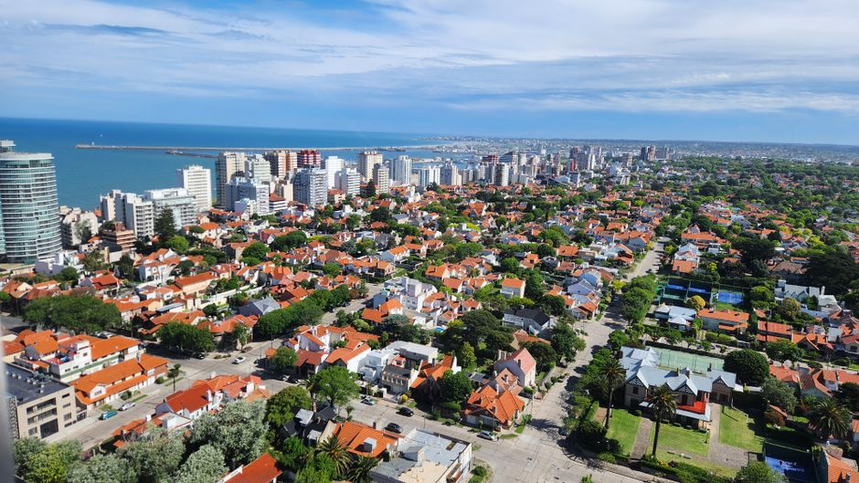 Best Helicopter over the Iguazu Falls, Transfer at Gran Meliá Iguazú Review 2026 - A scenic aerial view of a coastal city with red-roofed houses and modern skyline under a bright blue sky.