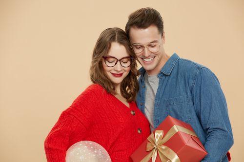 Free Happy couple wearing glasses exchanging gifts in a festive atmosphere. Stock Photo