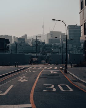 Urban cityscape of Seoul with Namsan Tower visible, capturing a quiet street scene.