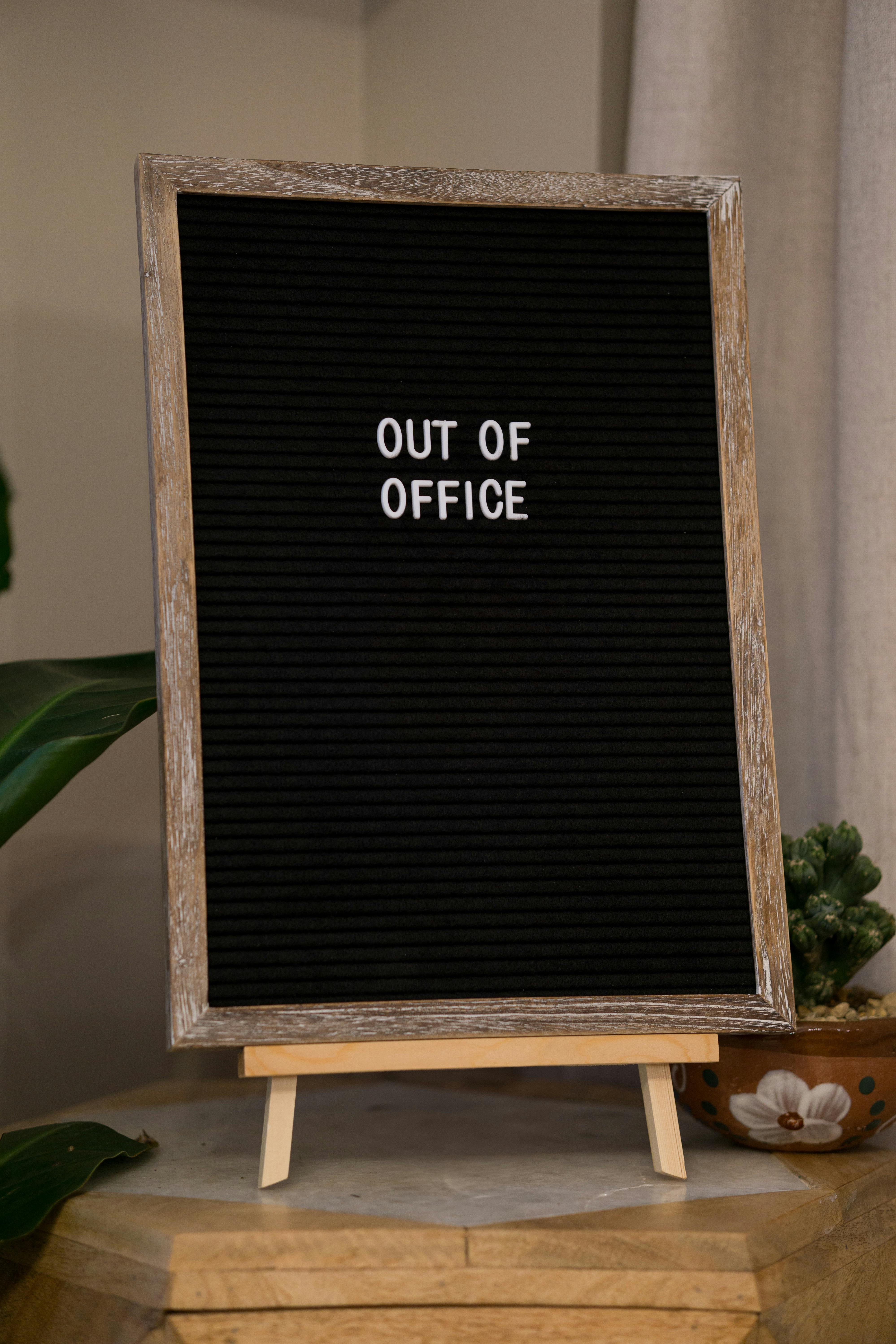 Kostnadsfria Dekorativ "Out of Office"-skylt i en mysig hemmiljö med växter. Stock foto