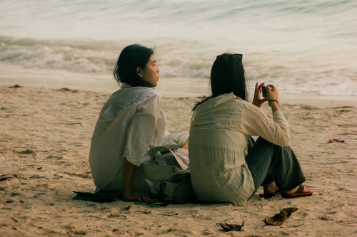 Free Two friends enjoying a peaceful moment on a sandy beach in Malay, Western Visayas, Philippines. Stock Photo