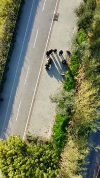 Drone view of people casting long shadows on road in Sanremo, Italy.