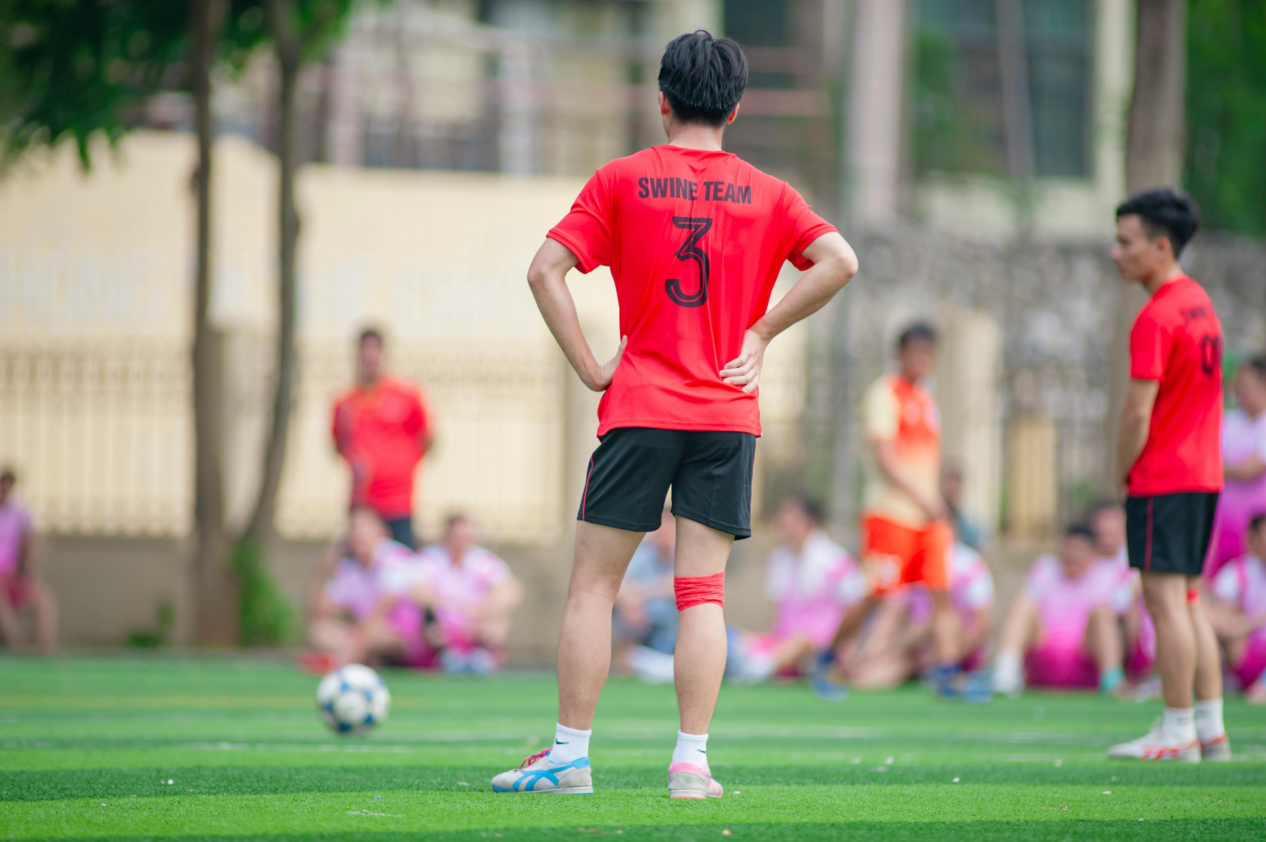 Amateur soccer players in vibrant jerseys on a field in Hanoi, Vietnam.
