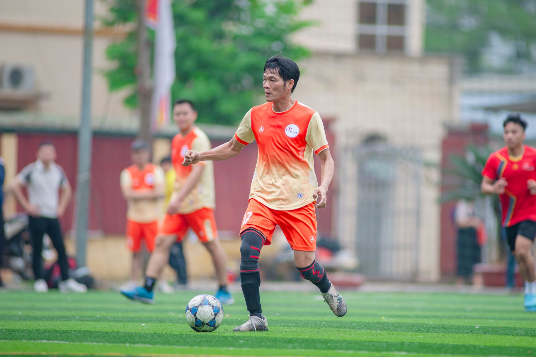 amateur football player completing a single-leg strength exercise with dumbbells inside a bright training facility