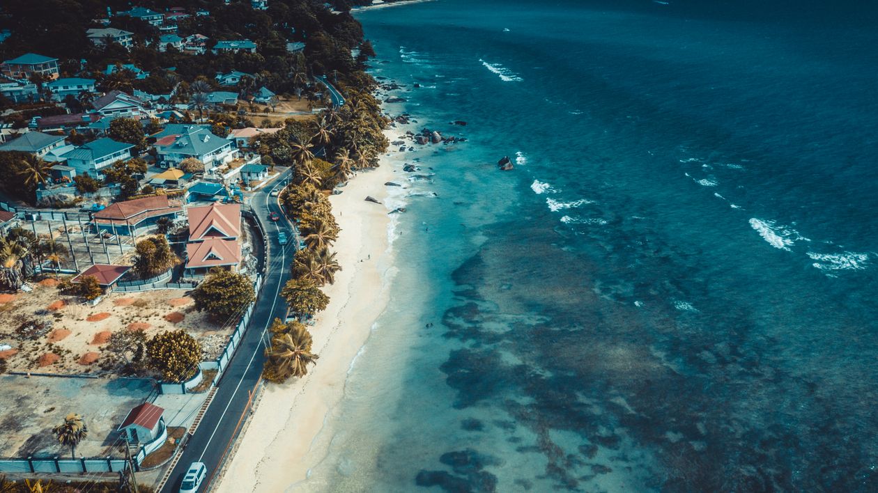 Free Stunning aerial view of a coastal neighborhood with ocean waves lapping at the shore. Stock Photo