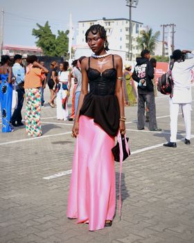 Elegant woman in a pink skirt and black top at outdoor fashion event