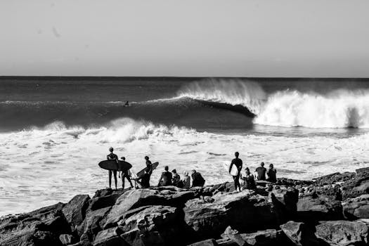 Black and white image of surfers observing waves at Taghazout beach.
