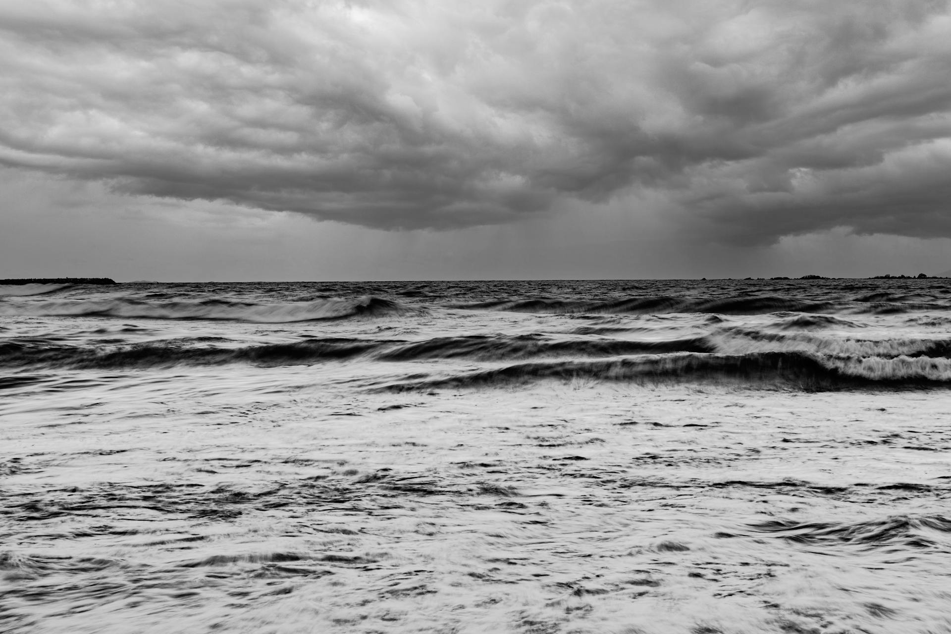 A stunning black and white ocean photograph showcasing dramatic storm clouds and waves.