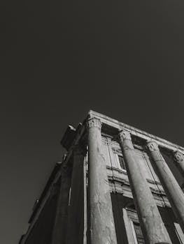 Black and white photo of a striking Roman temple with Corinthian columns under a moody sky.