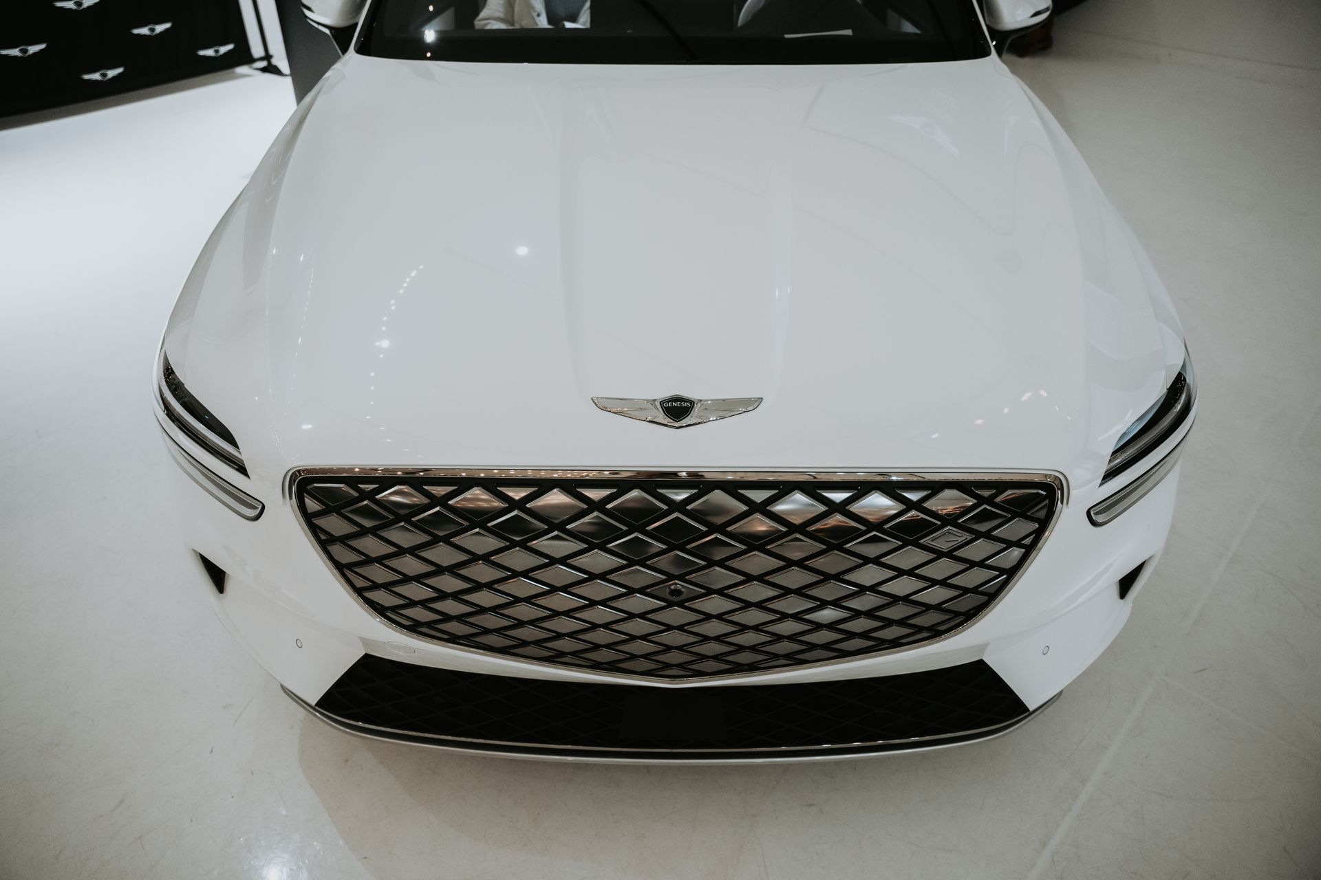 Close-up of a luxury white car showcasing its front grille in a modern showroom.