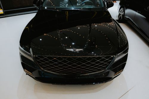 Free Close-up of a luxury black car hood reflecting showroom lights, front view. Stock Photo