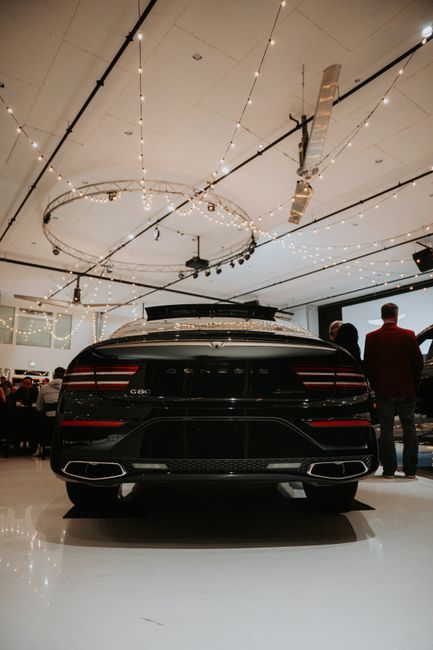 Genesis G80 in a luxury car showroom with elegant lighting and minimal crowd.