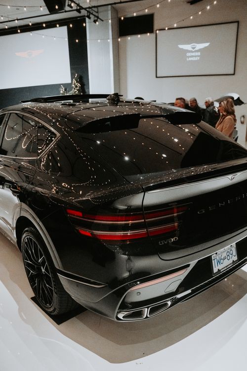 Free Sleek luxury SUV exhibited indoors with attendees in a sophisticated setting. Stock Photo