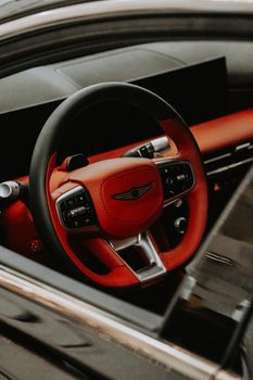 Close-up of a luxury car's interior featuring a red leather steering wheel. Modern and stylish design.