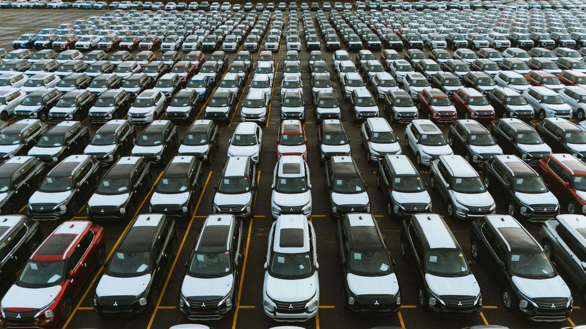 Aerial shot showcasing a vast storage lot filled with parked cars lined up in rows.