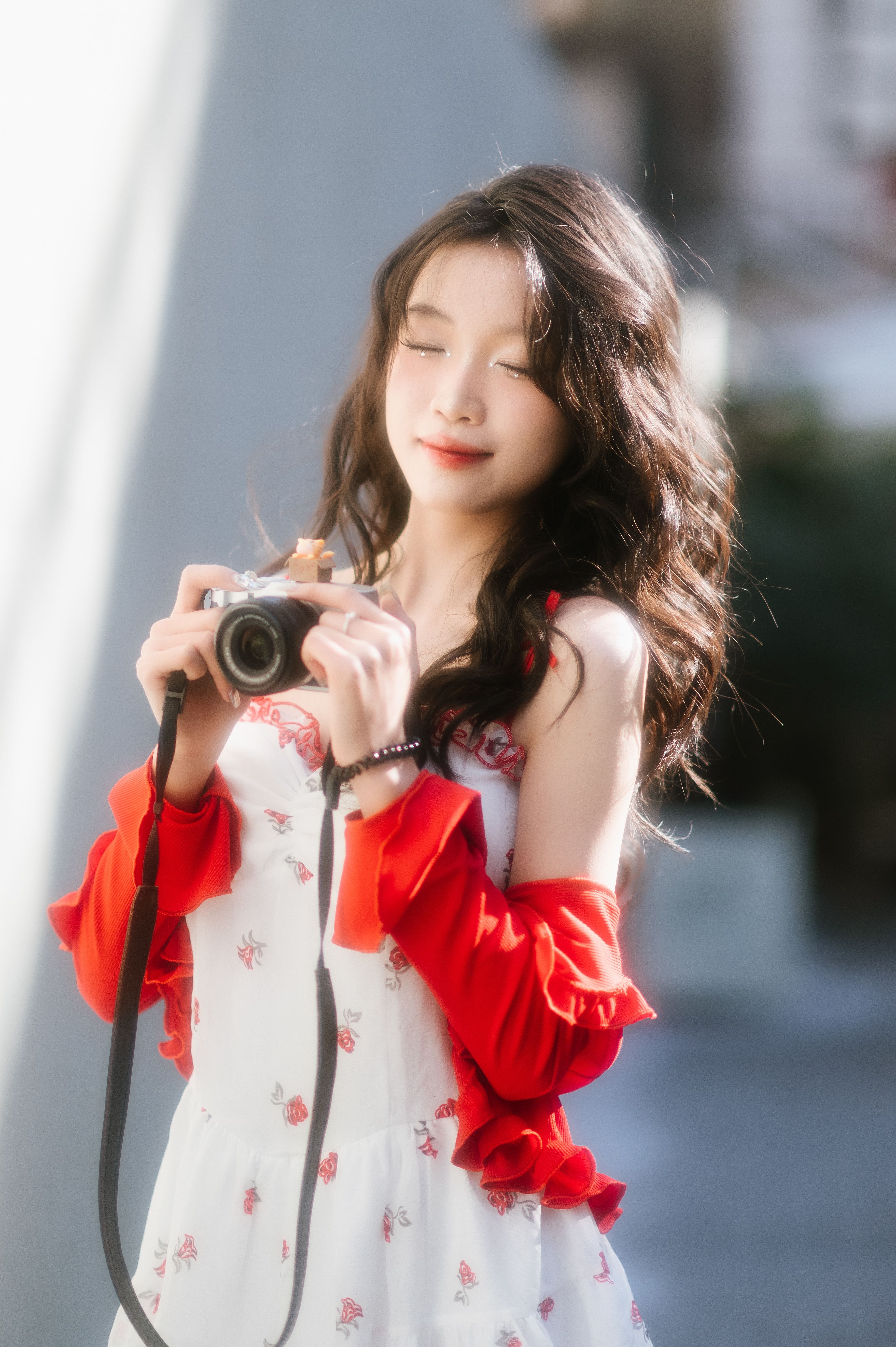 Charming young woman with a camera enjoying outdoor photography on a sunny day.