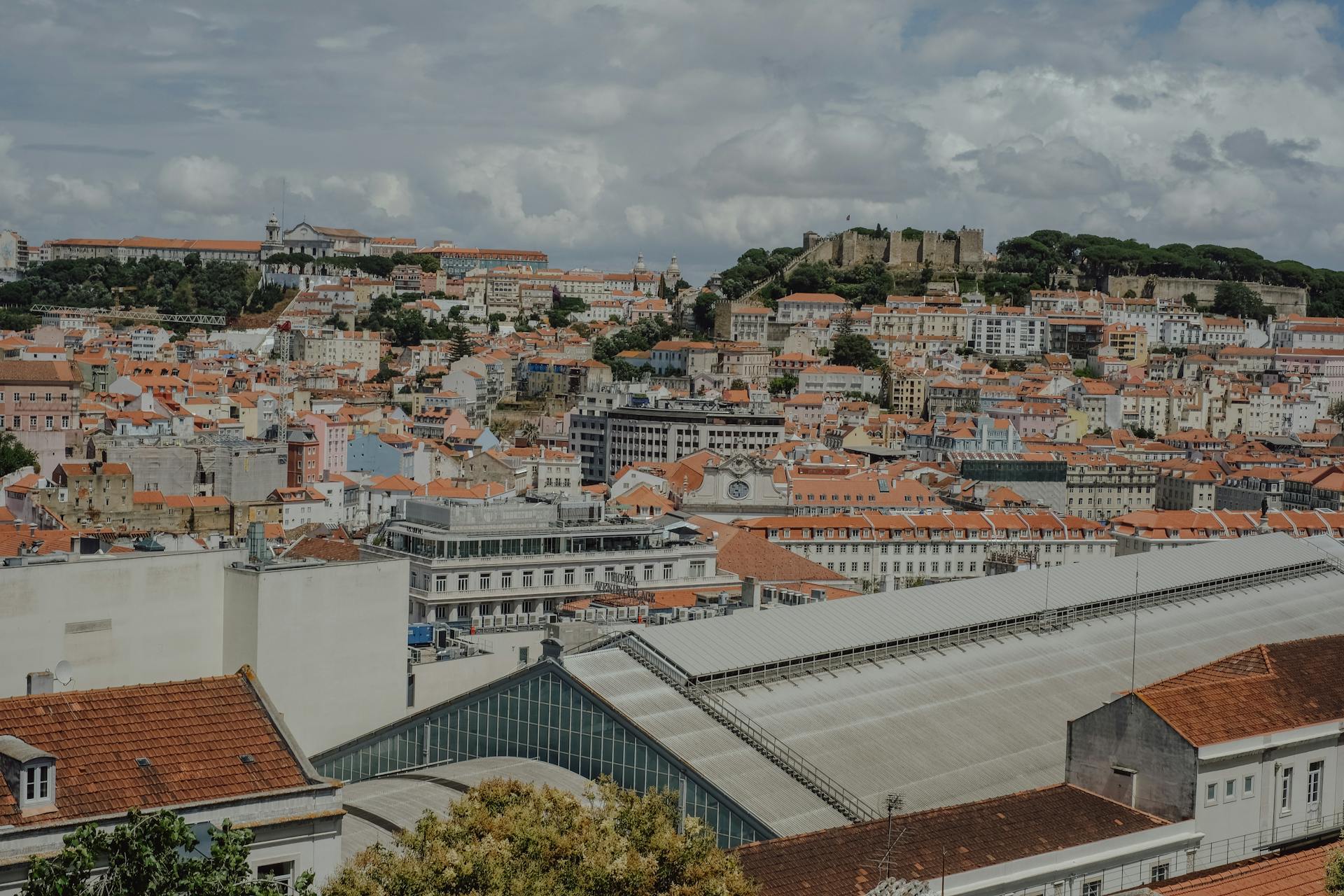 Aerial view of Lisbon showing historic buildings and São Jorge Castle under cloudy skies.