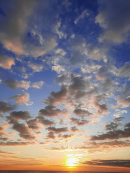 Breathtaking sunset over ocean with vibrant cloudscape and warm colors.