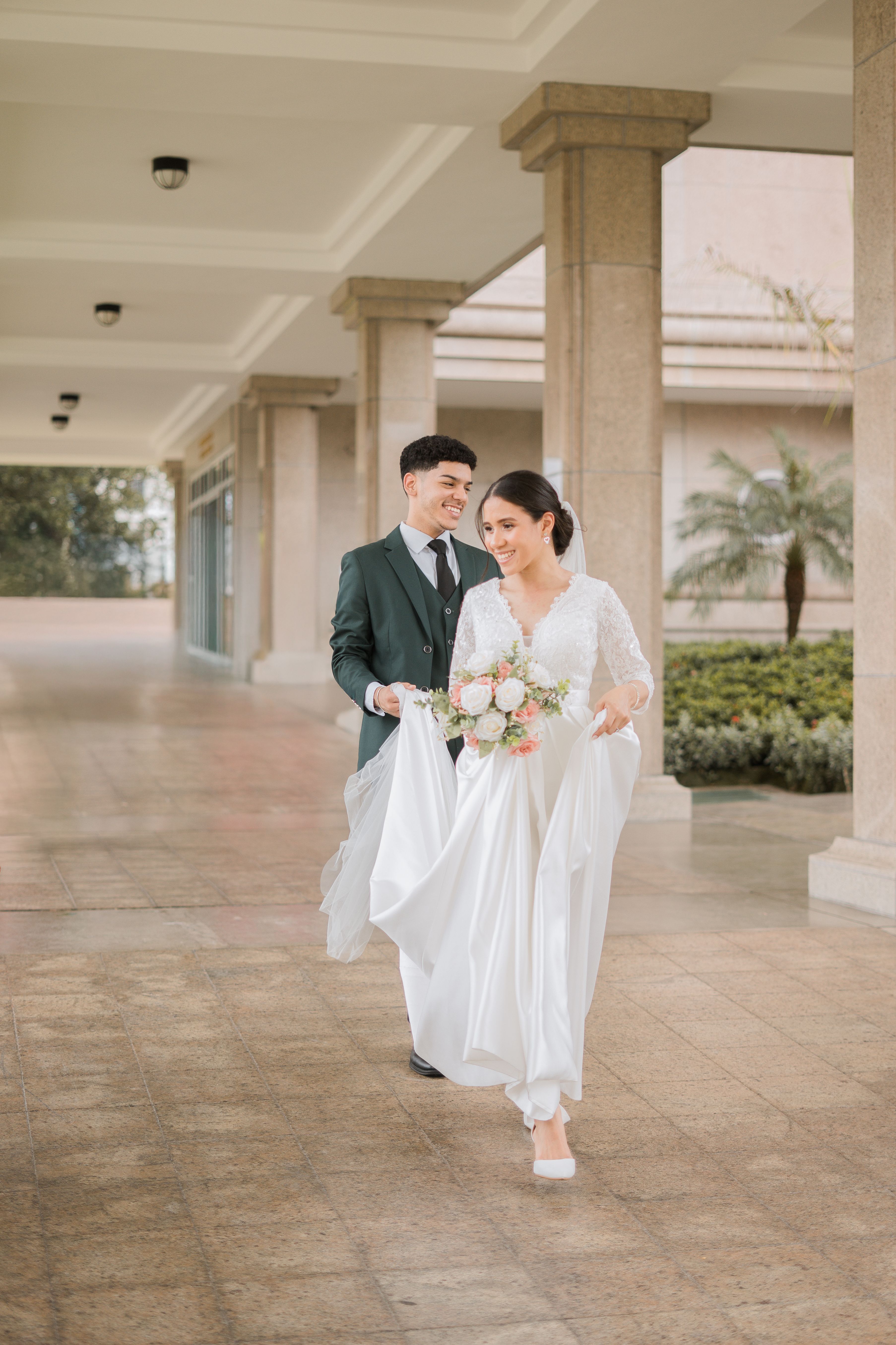 A joyful couple at their wedding in Santo Domingo, wearing elegant attire under a beautiful colonial-style structure.