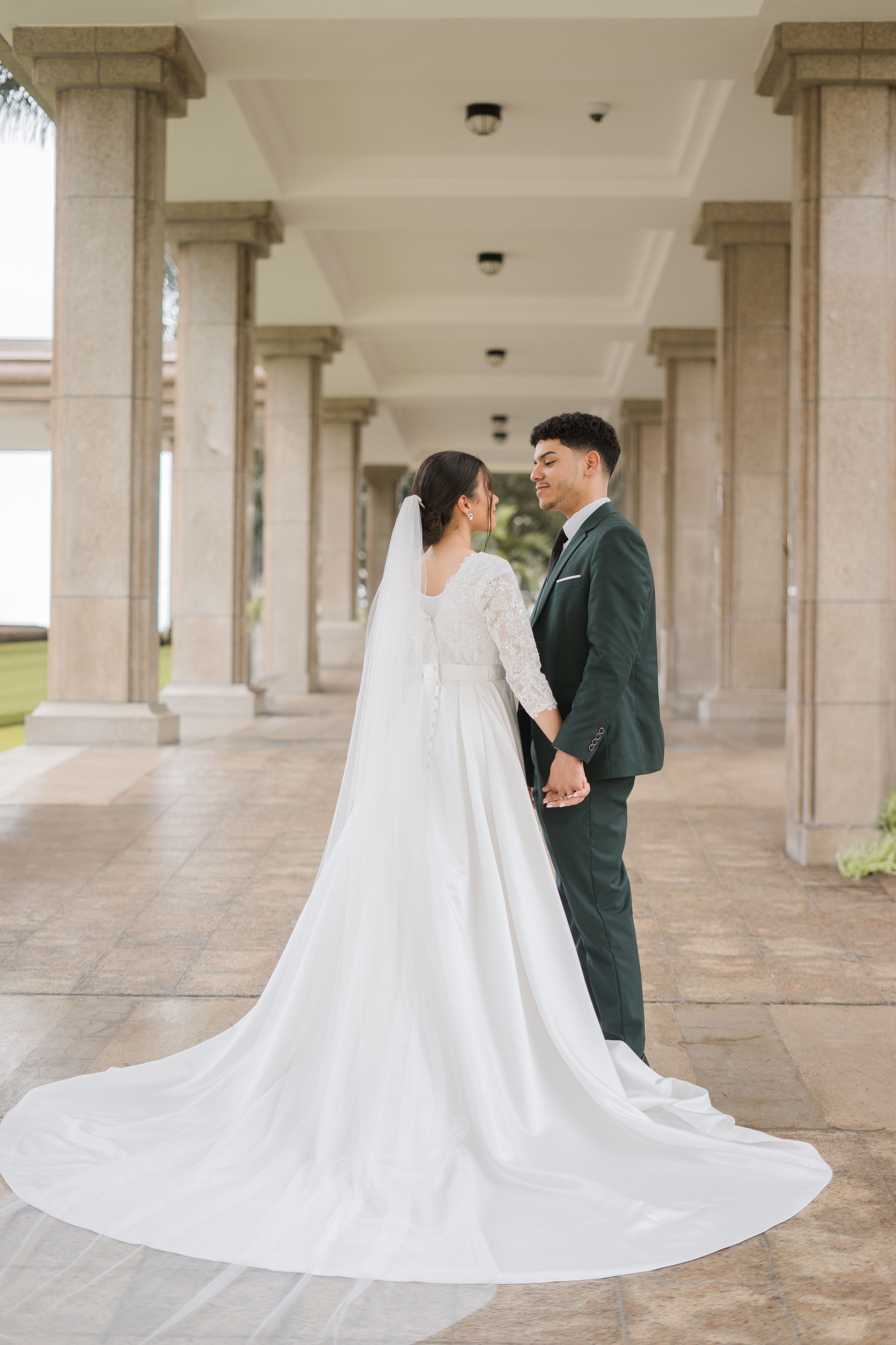 A bride and groom holding hands under a grand archway in Santo Domingo, Dominican Republic.