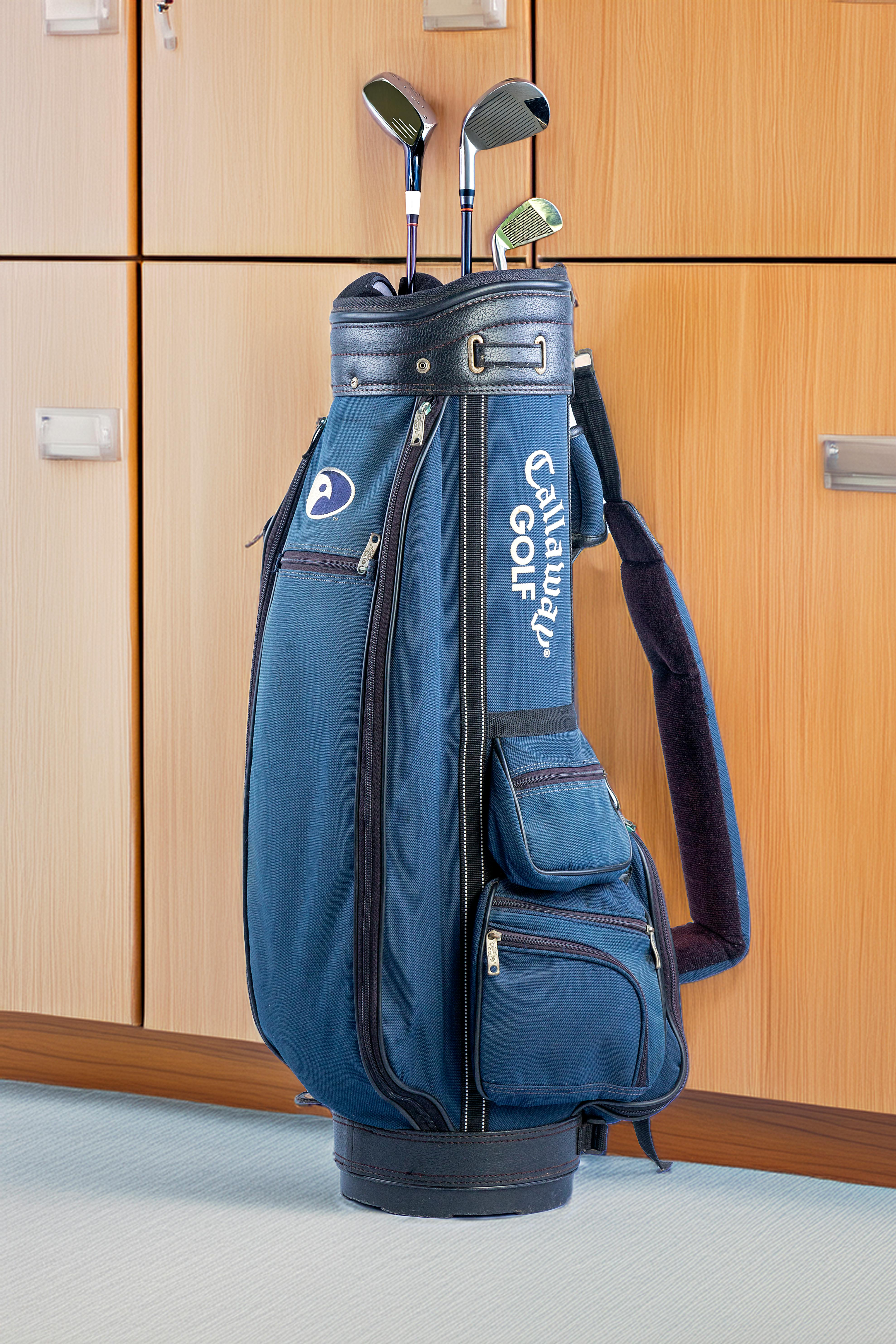 Blue golf bag with clubs in an indoor locker room, ideal for sports enthusiasts.