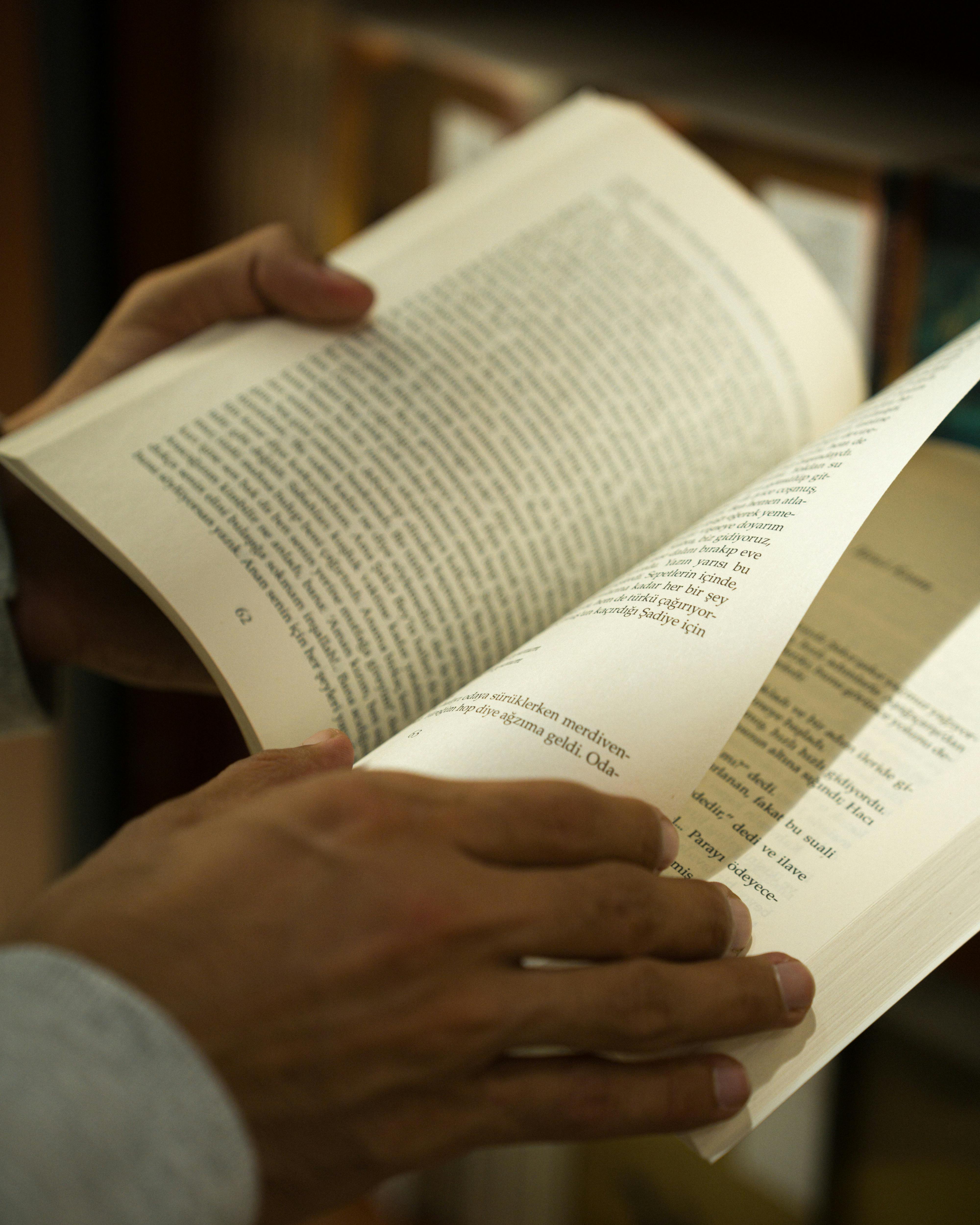 Ücretsiz Ankara'daki bir kütüphanede bir kitabın sayfalarını çeviren ellerin yakın çekimi. Stok Fotoğraflar