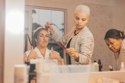 A joyful bride gets prepped for her big day by two professional stylists, adding final touches.