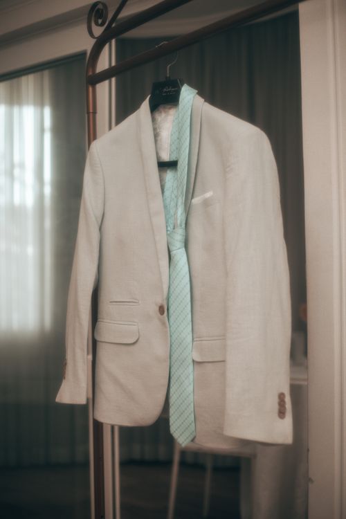 Free Stylish beige suit and blue tie hanging on a wooden hanger indoors, creating a sophisticated look. Stock Photo