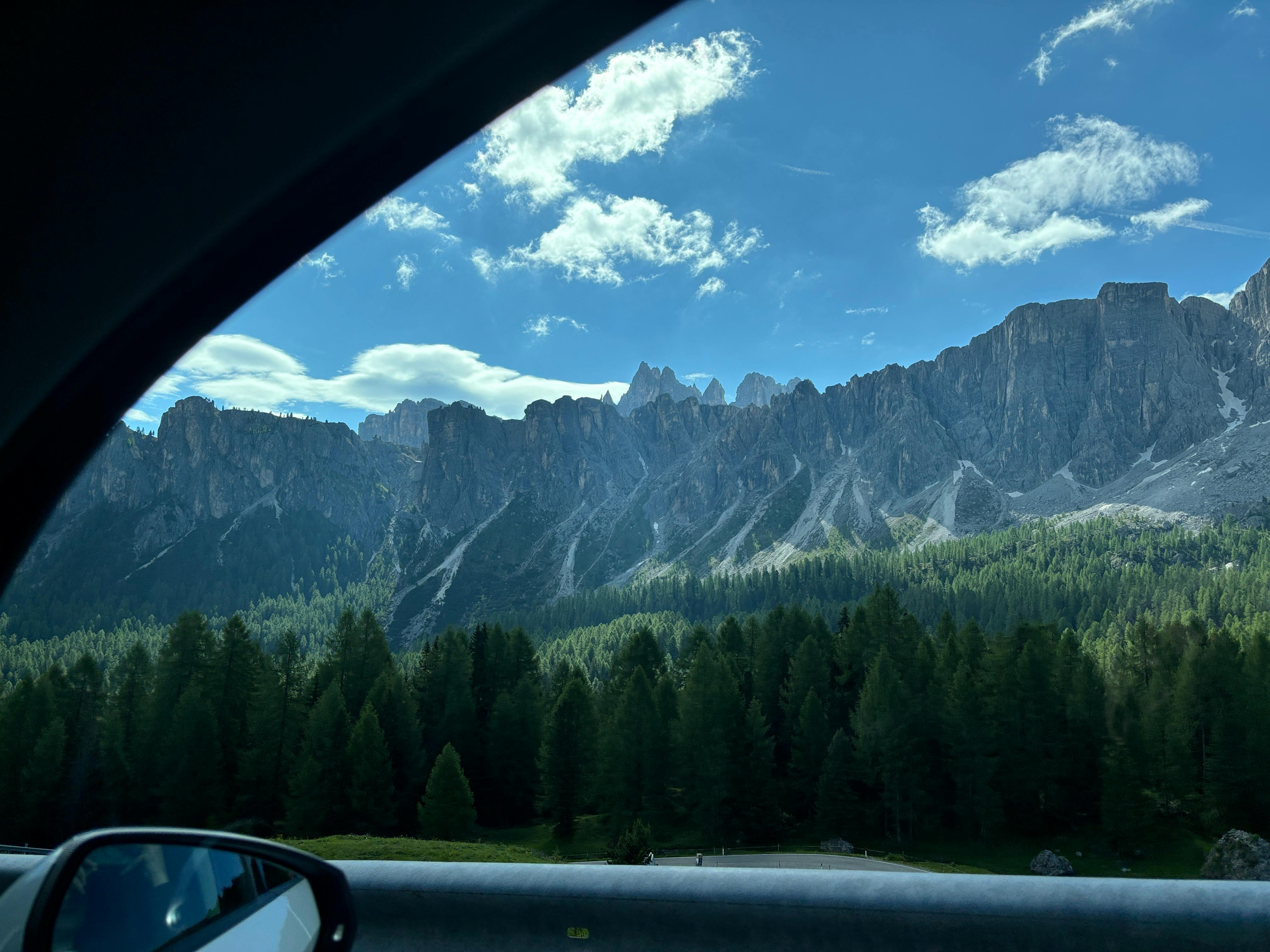 Breathtaking view of the Dolomite mountains from a car window on a sunny day in Italy.