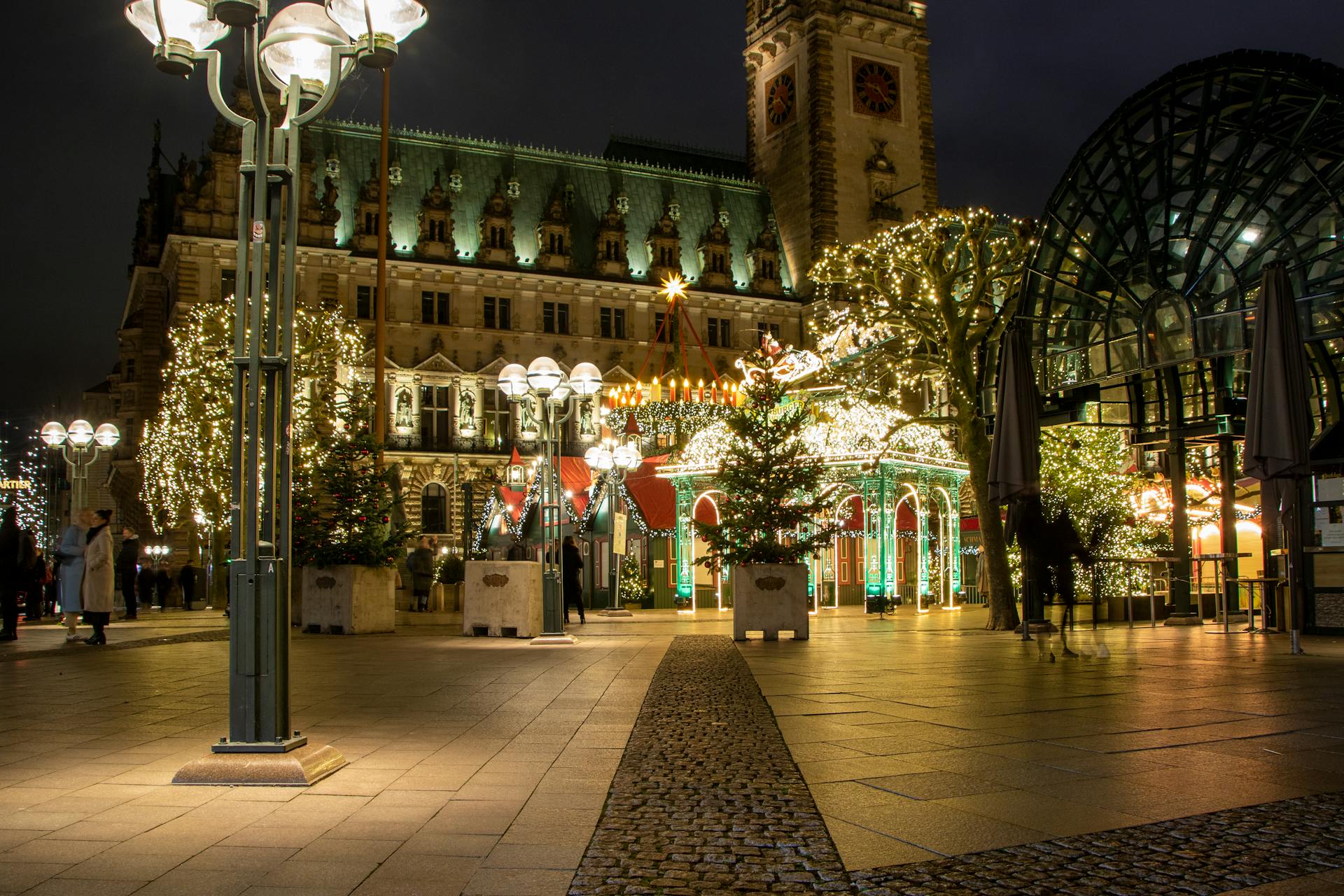 Festive night scene at Hamburg Christmas market, highlighting city hall lights and decorations.