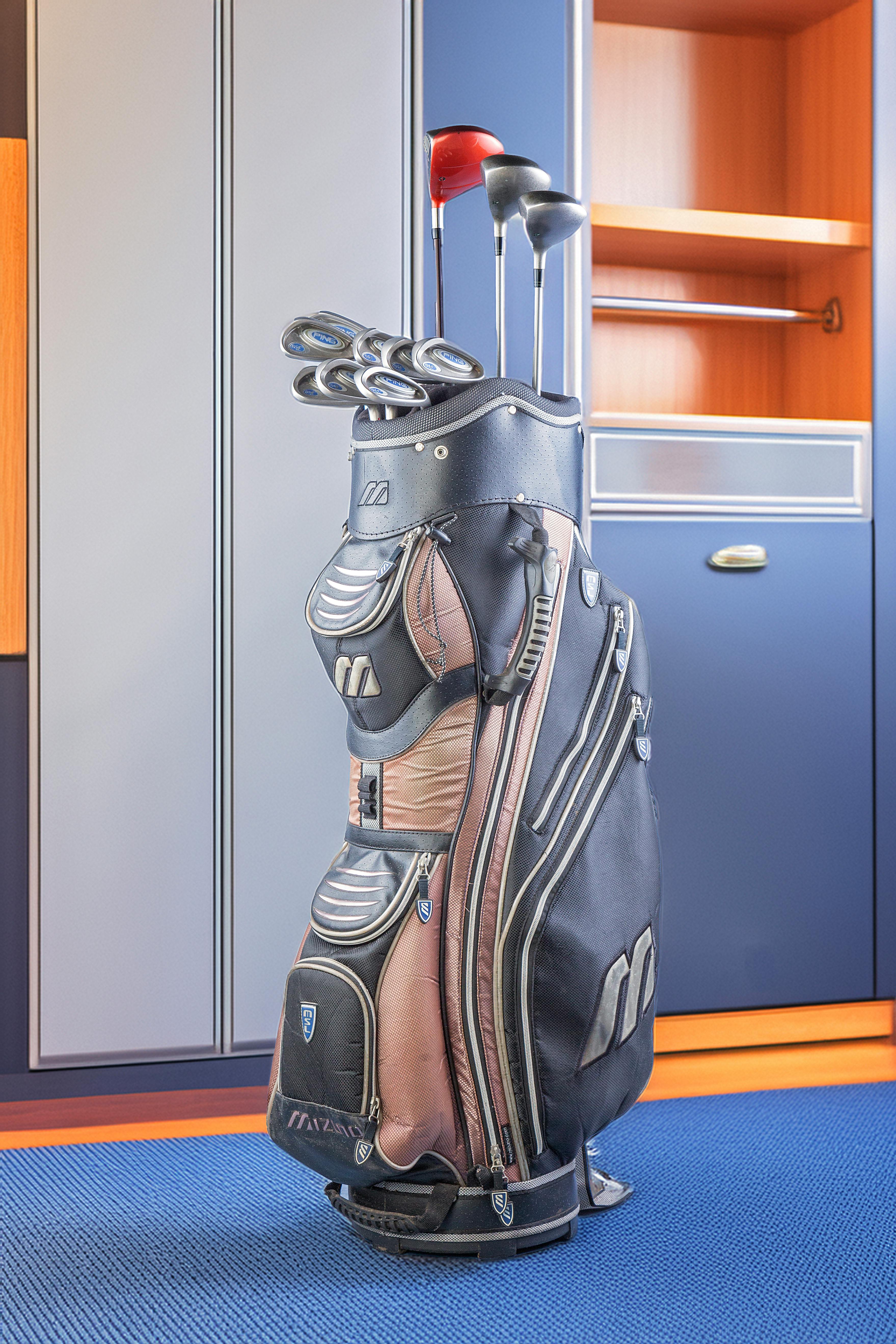 A golf bag with clubs stands in a modern locker room, ready for play.