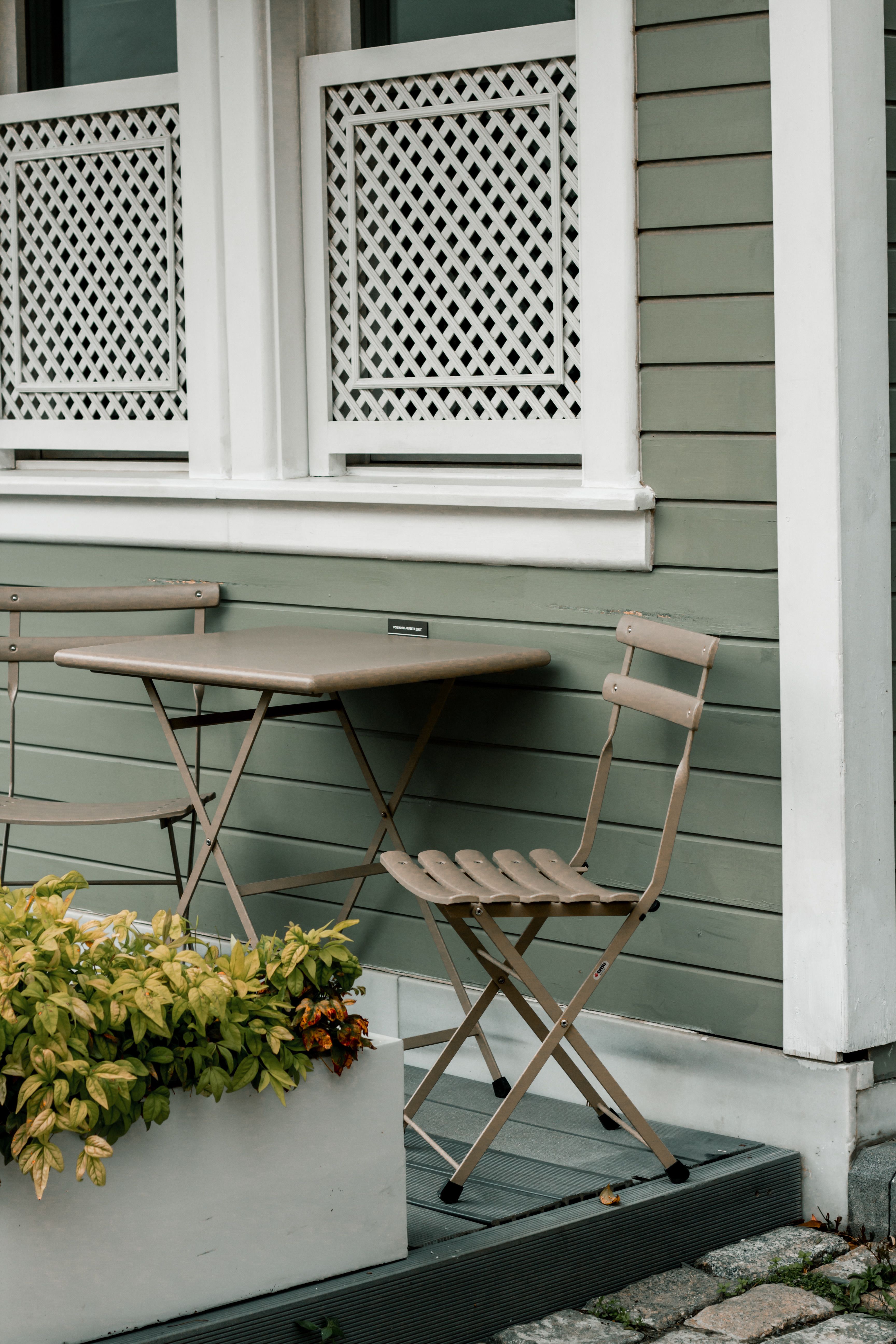 Charming outdoor setting with vintage chairs and table by a quaint building.