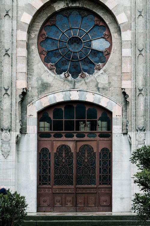 Free Elegant church facade featuring a stunning stained glass rose window and ornate iron doors. Stock Photo