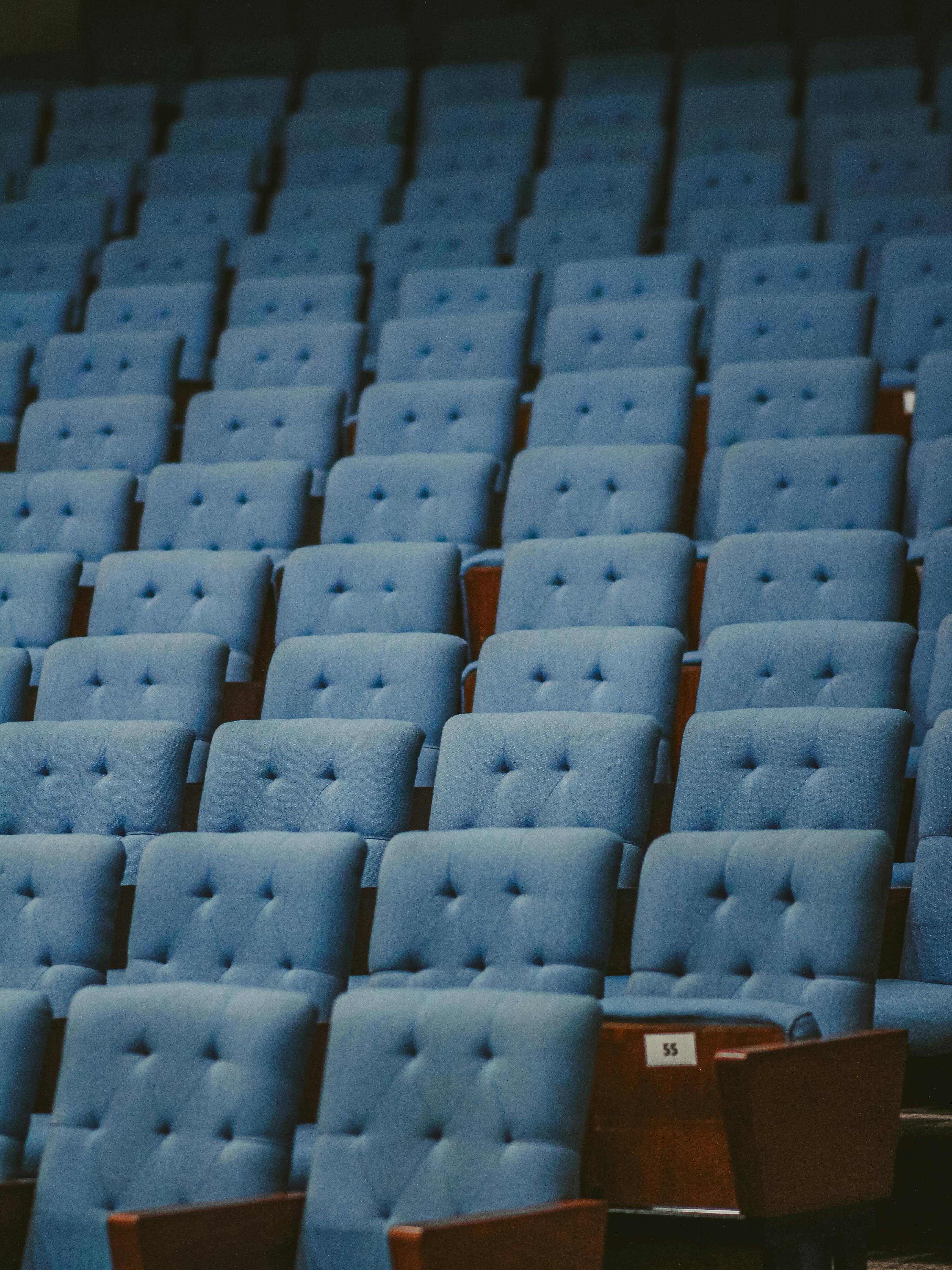 Gratis Sillas de auditorio azules dispuestas en filas ordenadas dentro de una moderna sala de conferencias, perfecta para eventos y reuniones. Foto de stock