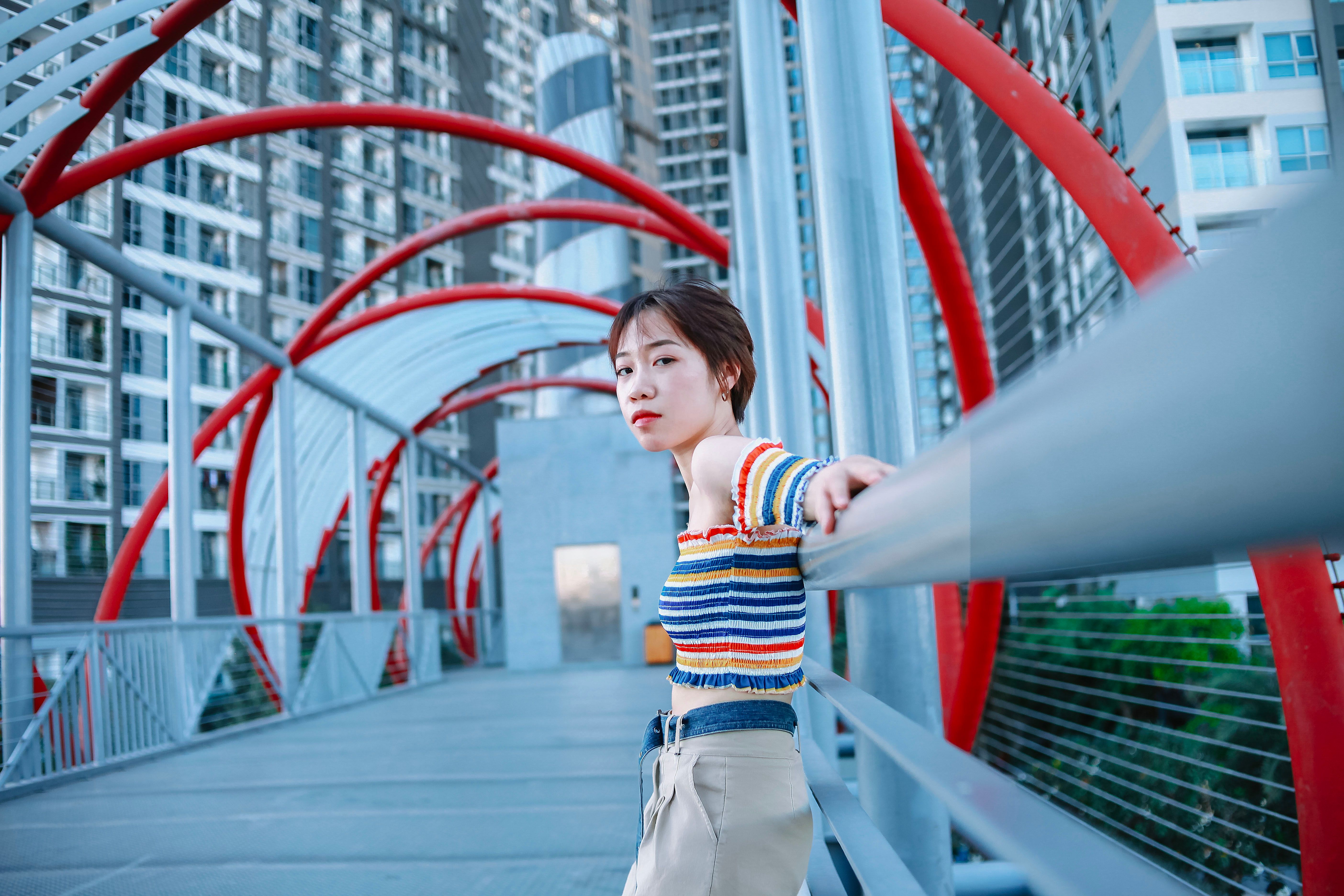 Confident woman on urban bridge, vibrant city backdrop