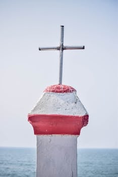 A white and red cross against a clear sky at Vagator Beach, Goa, India.