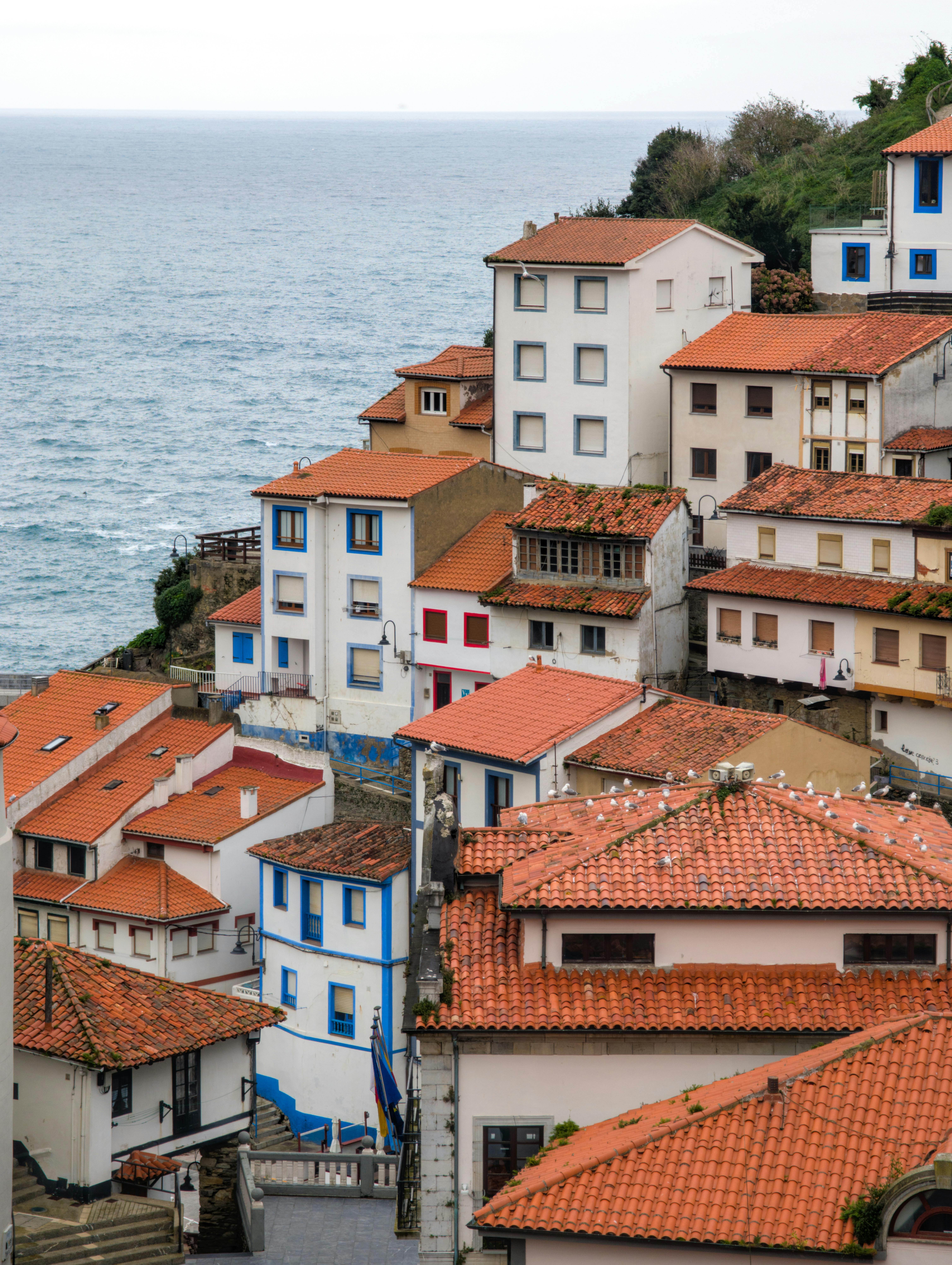 Colorful traditional village houses with red-tiled roofs overlooking the ocean in Cudillero, Spain.