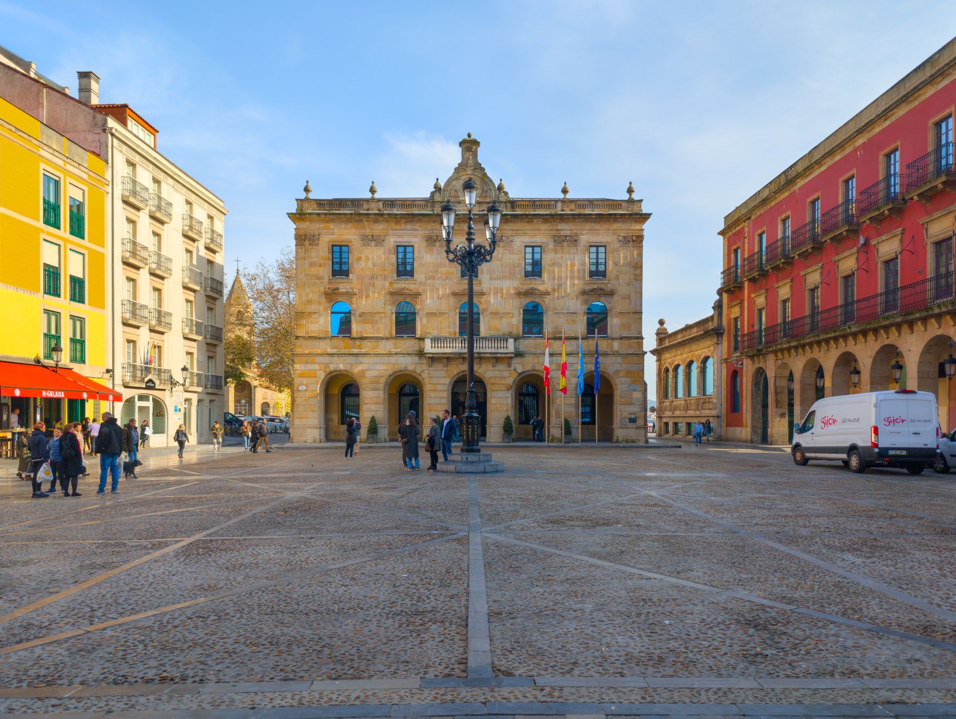 Sunny day in Gijón's Plaza Mayor showcasing Spanish architecture and urban lifestyle.