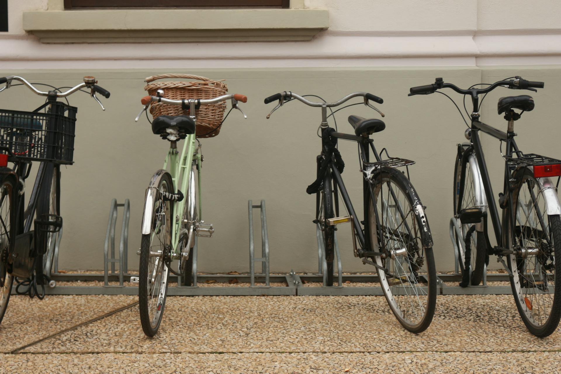 A row of bicycles parked in an urban bicycle rack outdoors, showcasing different bike styles.